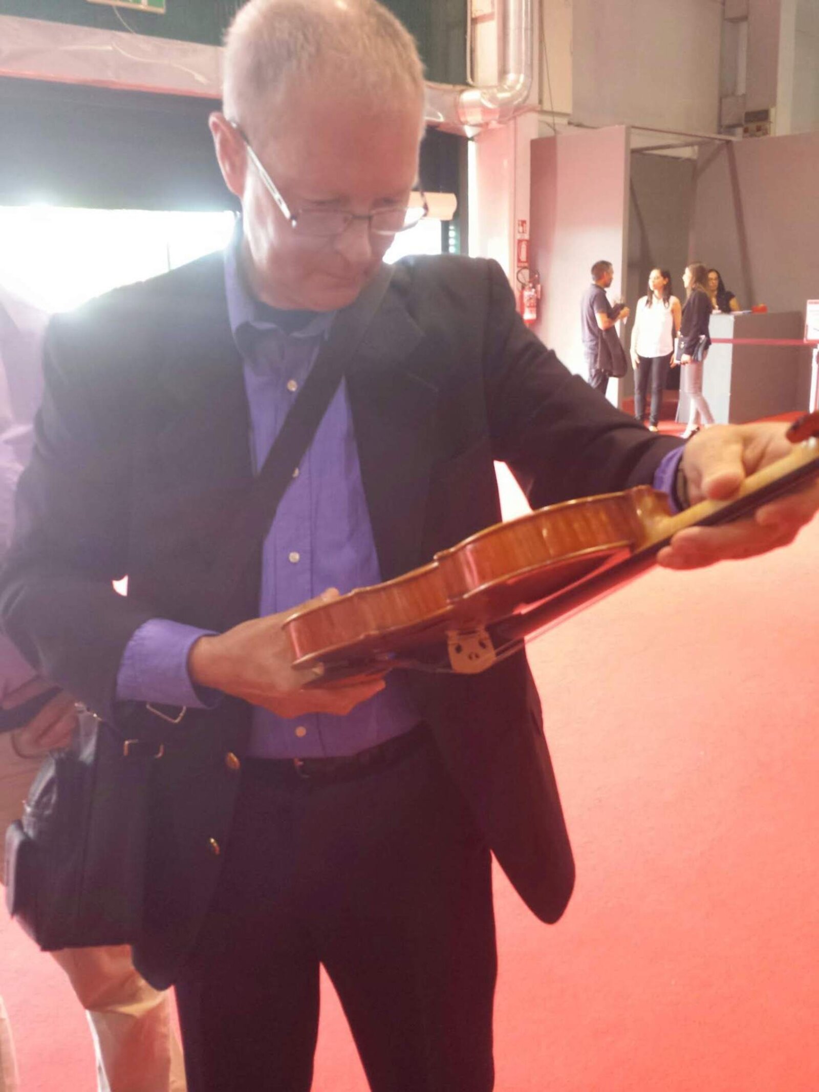 Dennis Braun inspecting the edge and varnish of a violin under the light at a trade fair